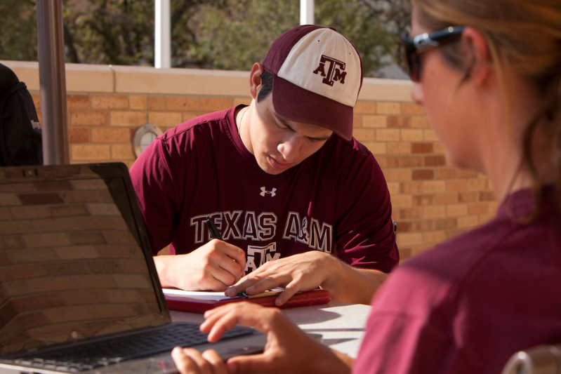 TAMU students sitting outdoor and working on their laptop